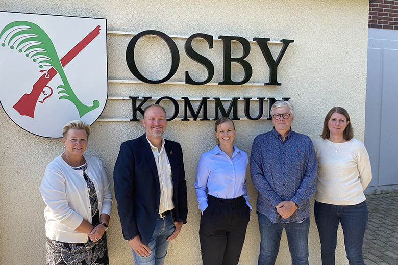 Representanter från B innovation och Osby kommun står framför Osby kommuns logotyp.