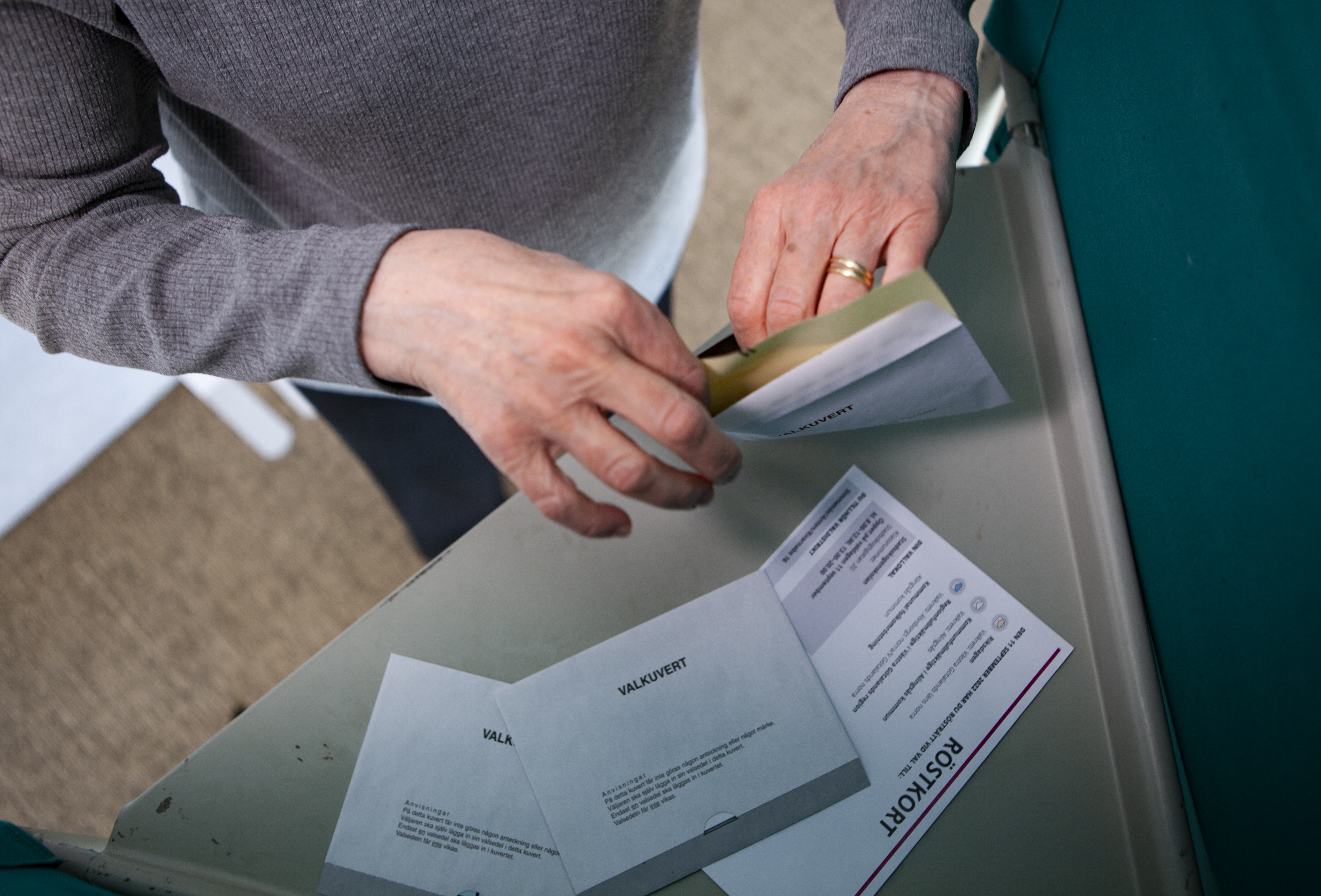En väljare står vid valbåset och stoppar ner sina röster i ett valkuvert. 
