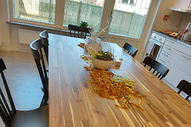 Ett stort avlångt matbord med svarta stolar. På bordet vilar gula serpentiner.