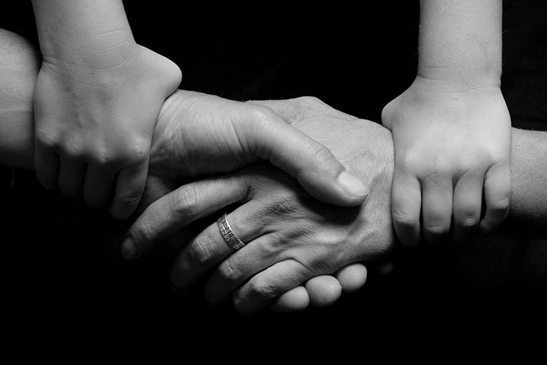 Barnhänder håller ihop sina föräldrars händer