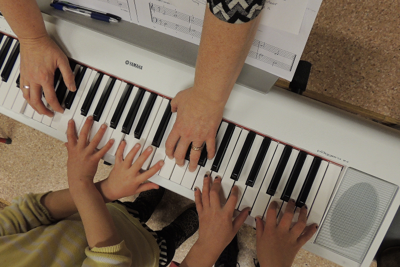 Elever och lärares händer som spelar på ett piano