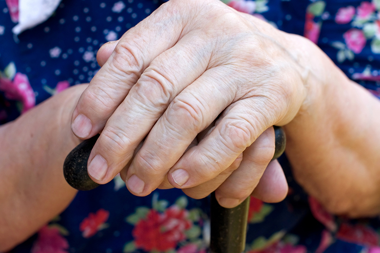 Äldre kvinna håller käpp