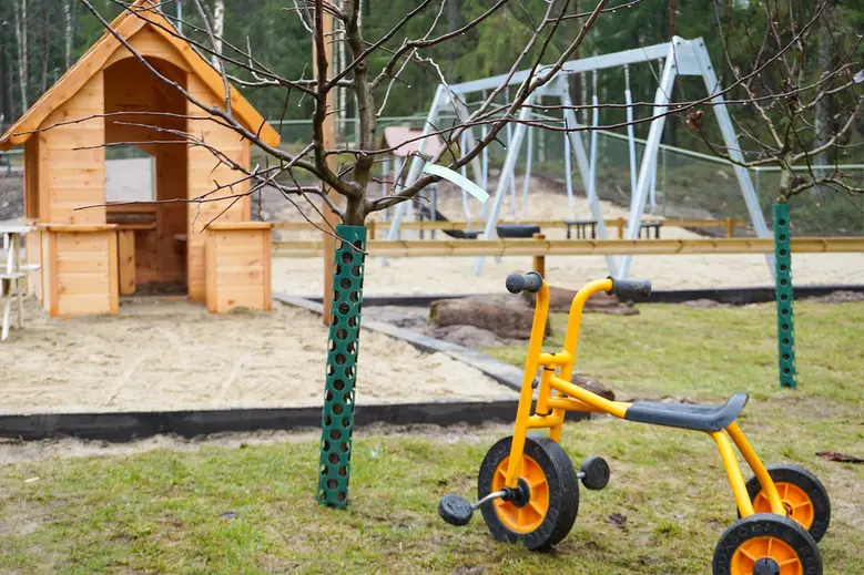 Utegården på Trulsagården. På bilden finns en trehjuling, lekstuga, gungor och fruktträd.